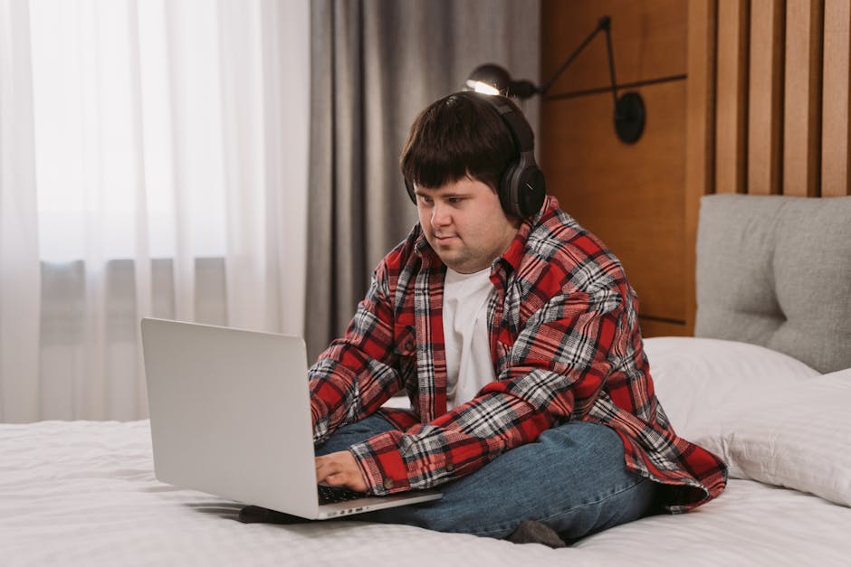 A person smiling while working on a laptop in a bright, modern living room.
